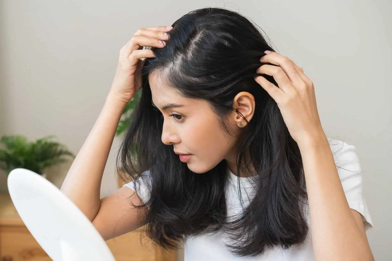 Woman checking her hairline and scalp in mirror in Niceville, FL | Blissful Beauty Bar